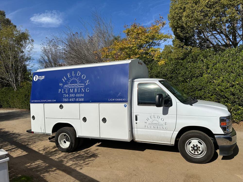 White service van for Sheldon Plumbing with blue branding and contact information.