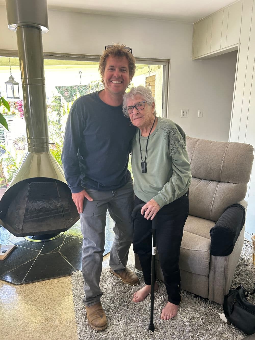 Smiling man and elderly woman in cozy living room, showcasing warmth and connection.