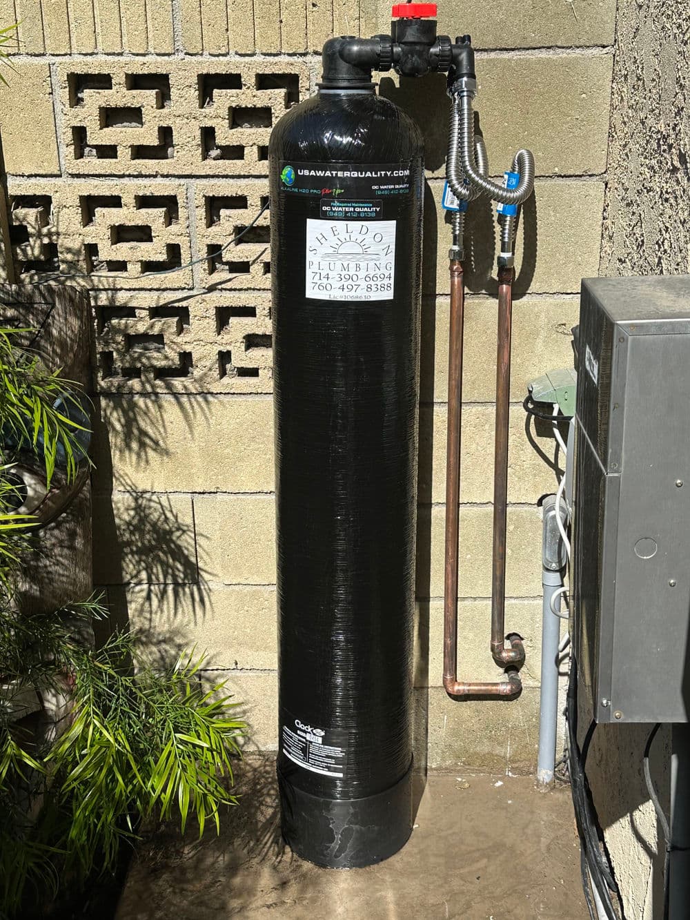 Water filtration system installed outdoors, featuring pipes and connections on a wall.